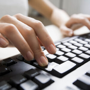 A female typing on a black computer keyboard