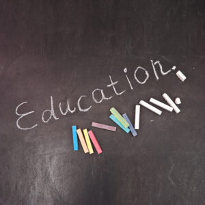 The word educatin written on a blackboard and various colors of chalk