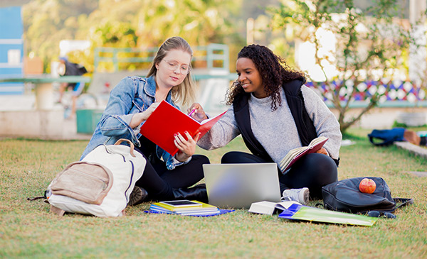two female college students sitting on a lawn