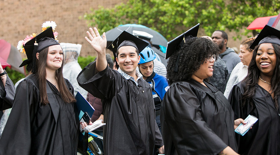 CCC graduate standing in a group waving hi with his hand