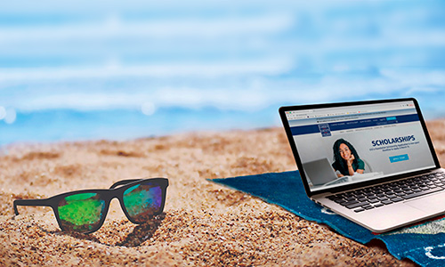 laptop and sunglasses sitting in the sand by the ocean