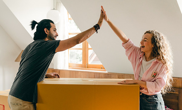 man and woman performing a high five while moving into a house