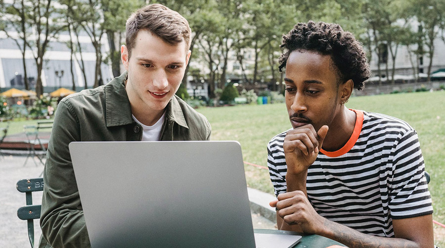two young men looking at a laptop on campus